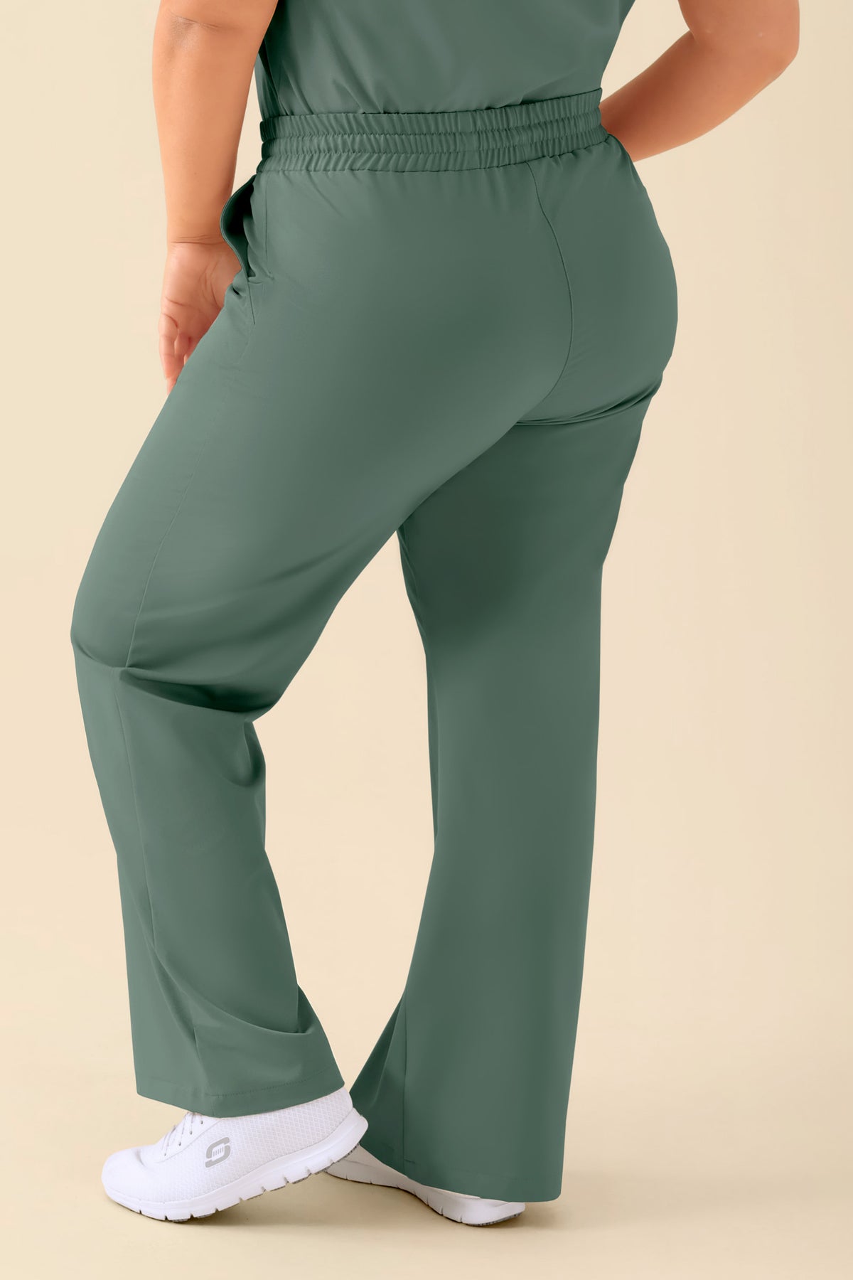 KAERE Damenhose – weites Bein, dunkelgrün, in einer bequemen, lässigen Weite mit elastischem Bund, kombiniert mit weißen Sneakers., Rückansicht