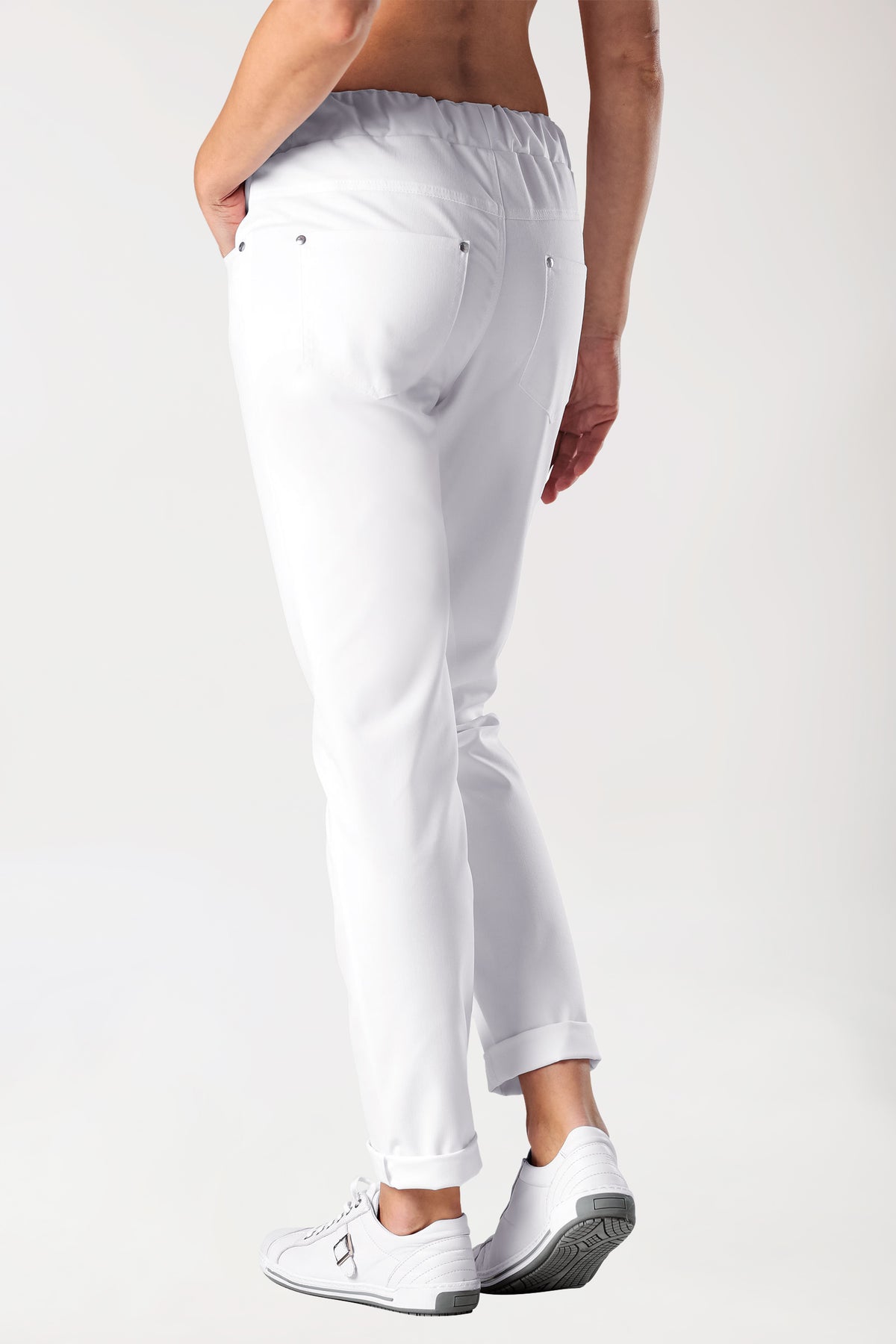 Frau in einer weißen 5-Pocket-Stretchhose für Damen – Hose im Jeans-Look mit Umschlag und weißen Sneakers.