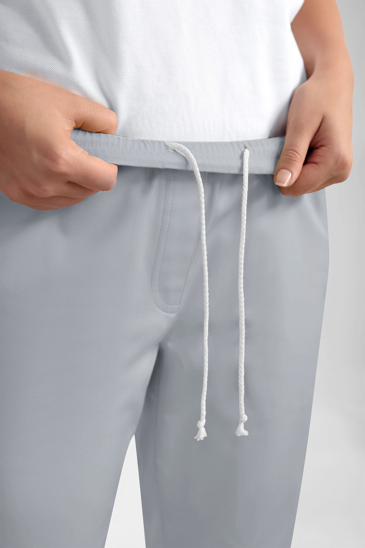 Hände, die den elastischen Bund der GRÜNEN Stretchhose für Damen – im Jogginghosen-Stil, perlgrau – mit lässiger Beinweite festhalten.