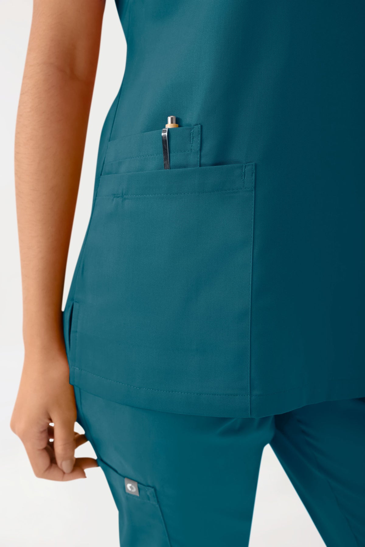 GREEN Stretch-Schlupfkasack für Damen – Scrub-Oberteil in Petrol mit V-Ausschnitt, einer aufgesetzten Brusttasche mit Stifthalter und Seitentaschen.
