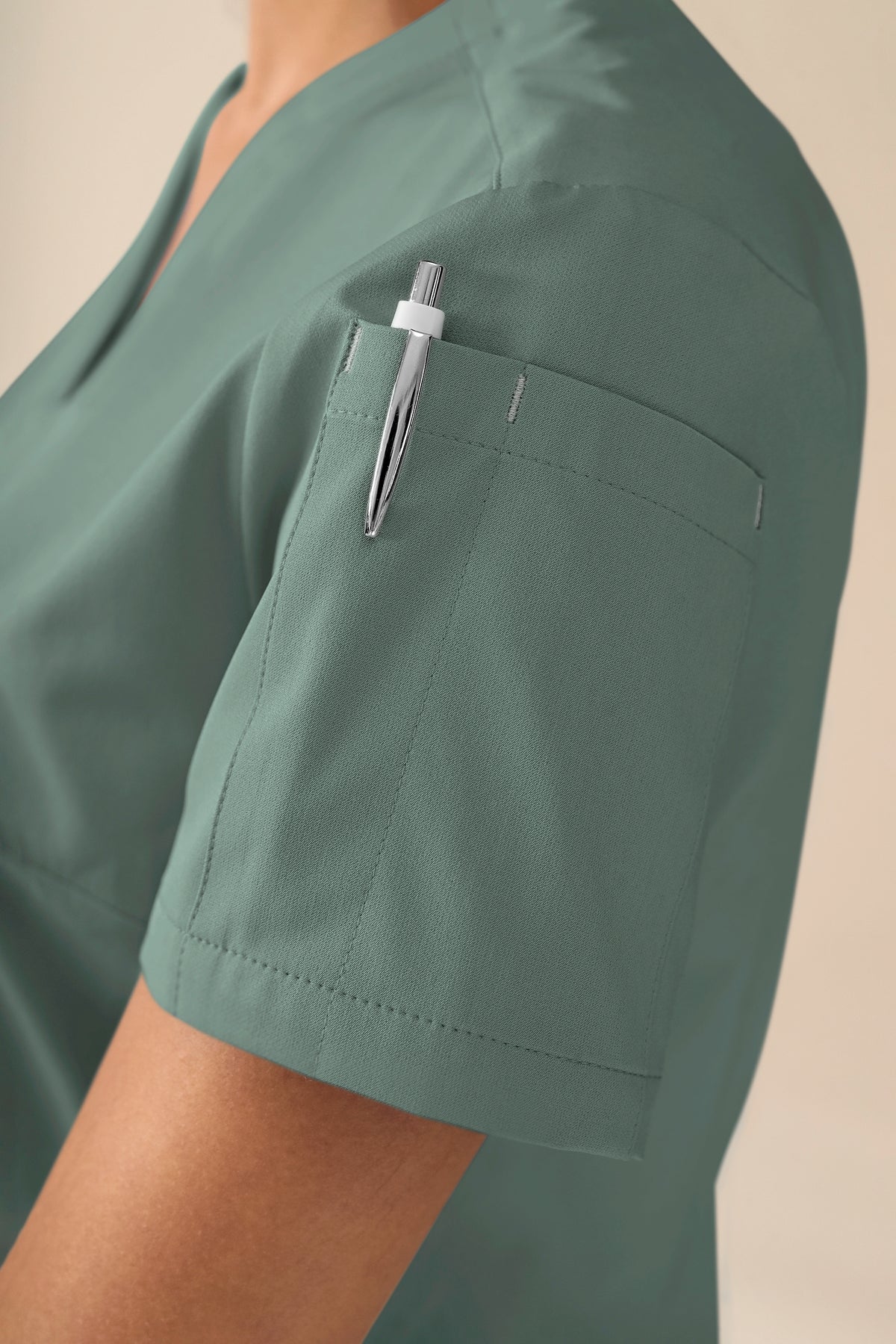 KAERE Damen-Schlupfjacke – V-Ausschnitt, dunkelgrün, mit Seitentaschen und einem Stift in der Ärmeltasche.