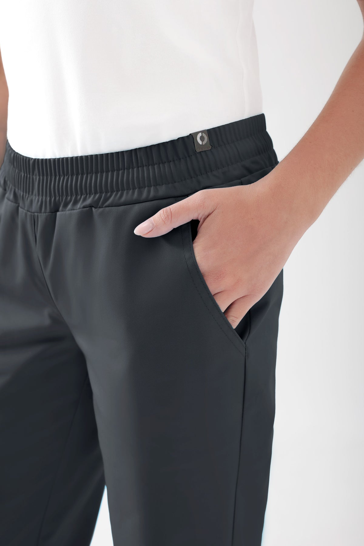 Eine Person, die eine Hose der Marke JUST STRONG Hose Damen – Gummibund anthrazit trägt, mit Kordelzug am Bund und Seitentaschen.