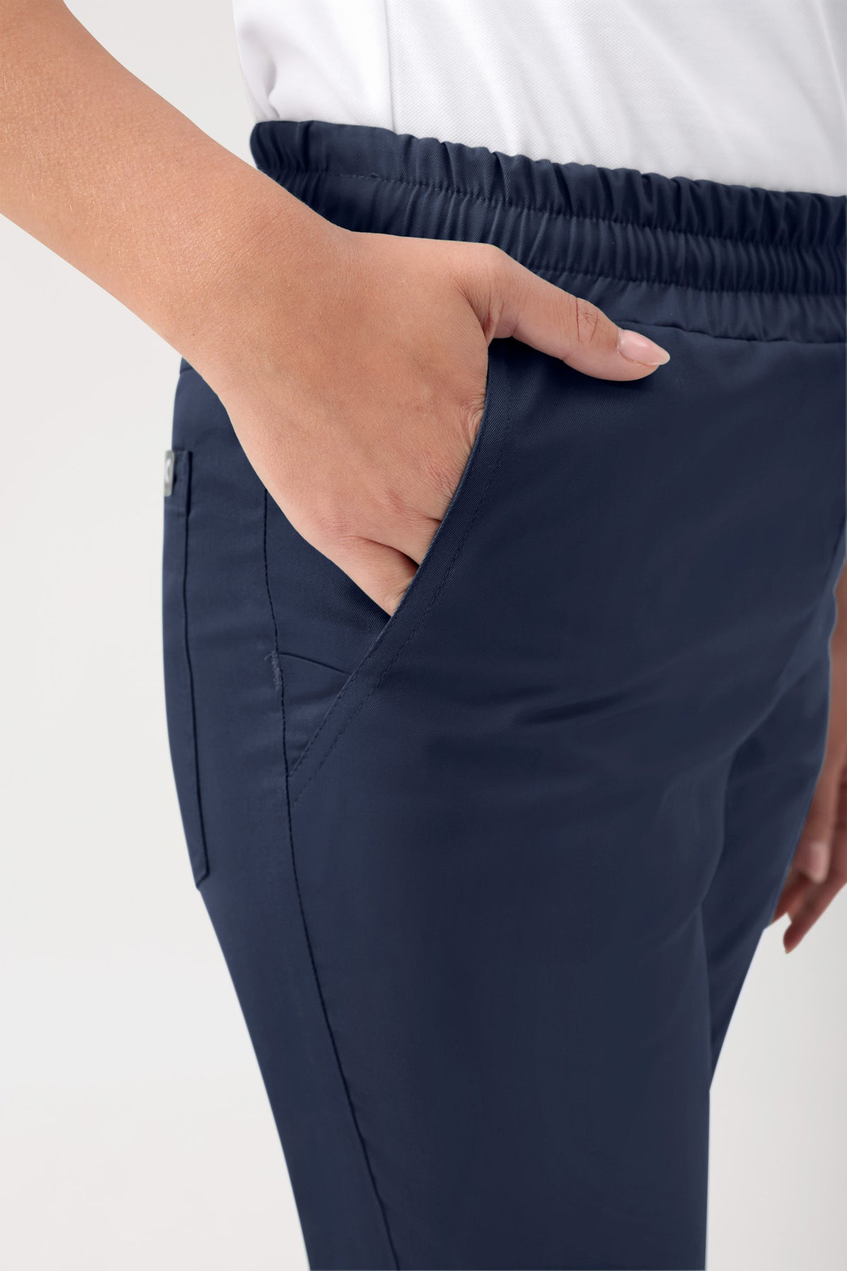 Eine Person trägt eine marinegrüne Stretch-Hose Unisex – Rundumgummibund mit bequemem elastischem Bund und einer Seitentasche sowie einer lässigen Beinweite.