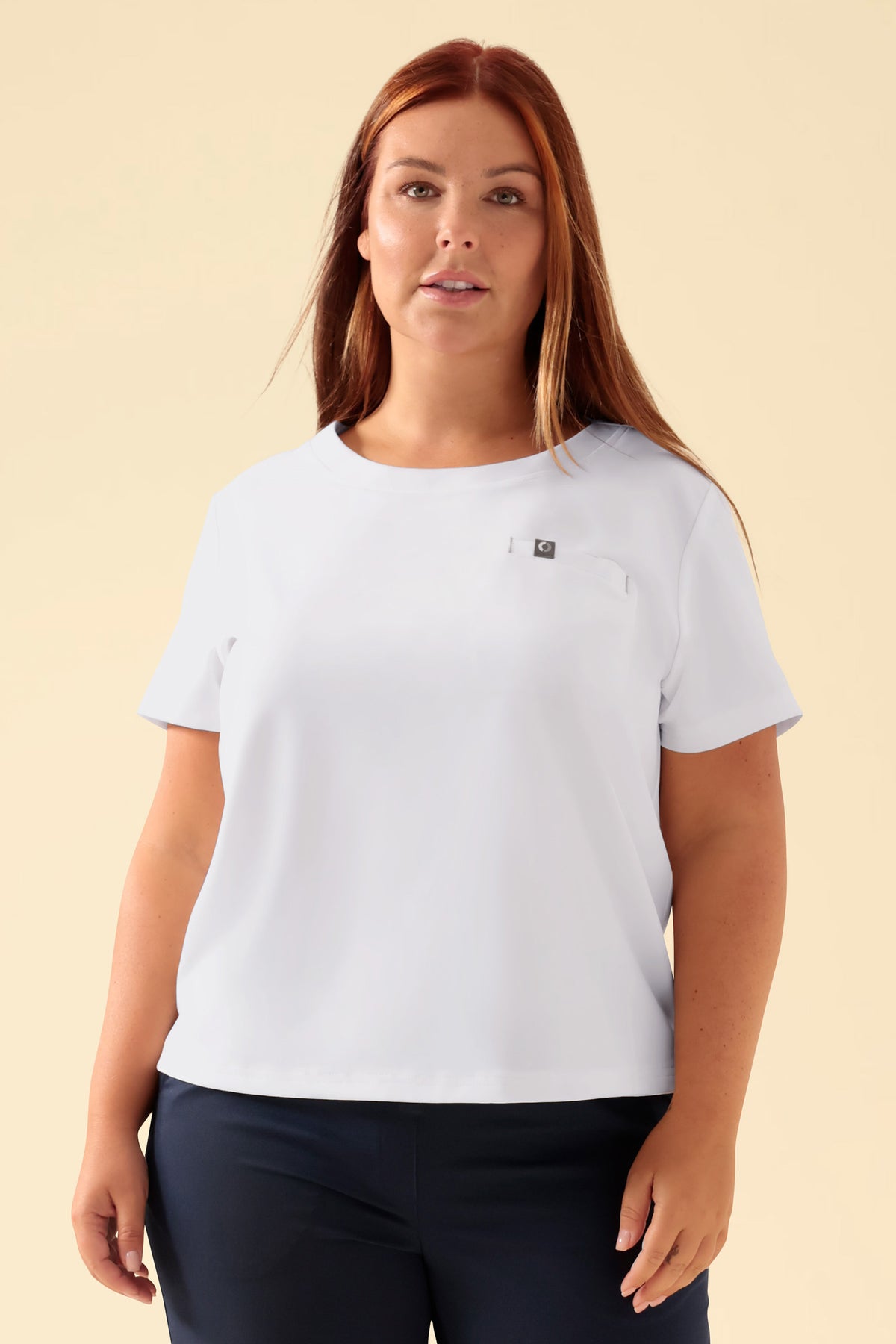 Frau in einem weißen KAERE Shirt Damen – Rundhalsausschnitt, einem antibakteriellen Kurzarm-T-Shirt mit Rundhalsausschnitt und einer kleinen Brusttasche., Vorderansicht Das Model ist 173 cm groß und trägt Größe XL
