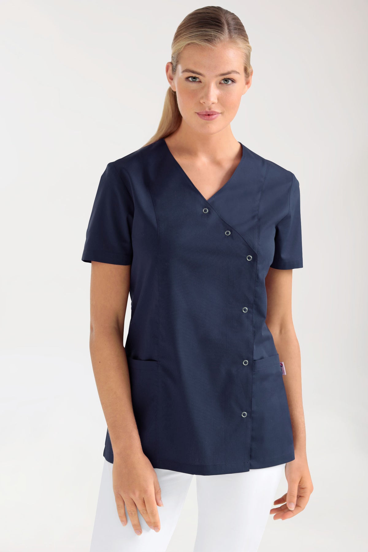 Eine Frau, die einen marineblauen Stretch Kasack Damen – durchgeknöpft navy trägt, eine kurzärmelige Tunika mit V-Ausschnitt, diagonaler Druckknopfleiste und zwei Seitentaschen.