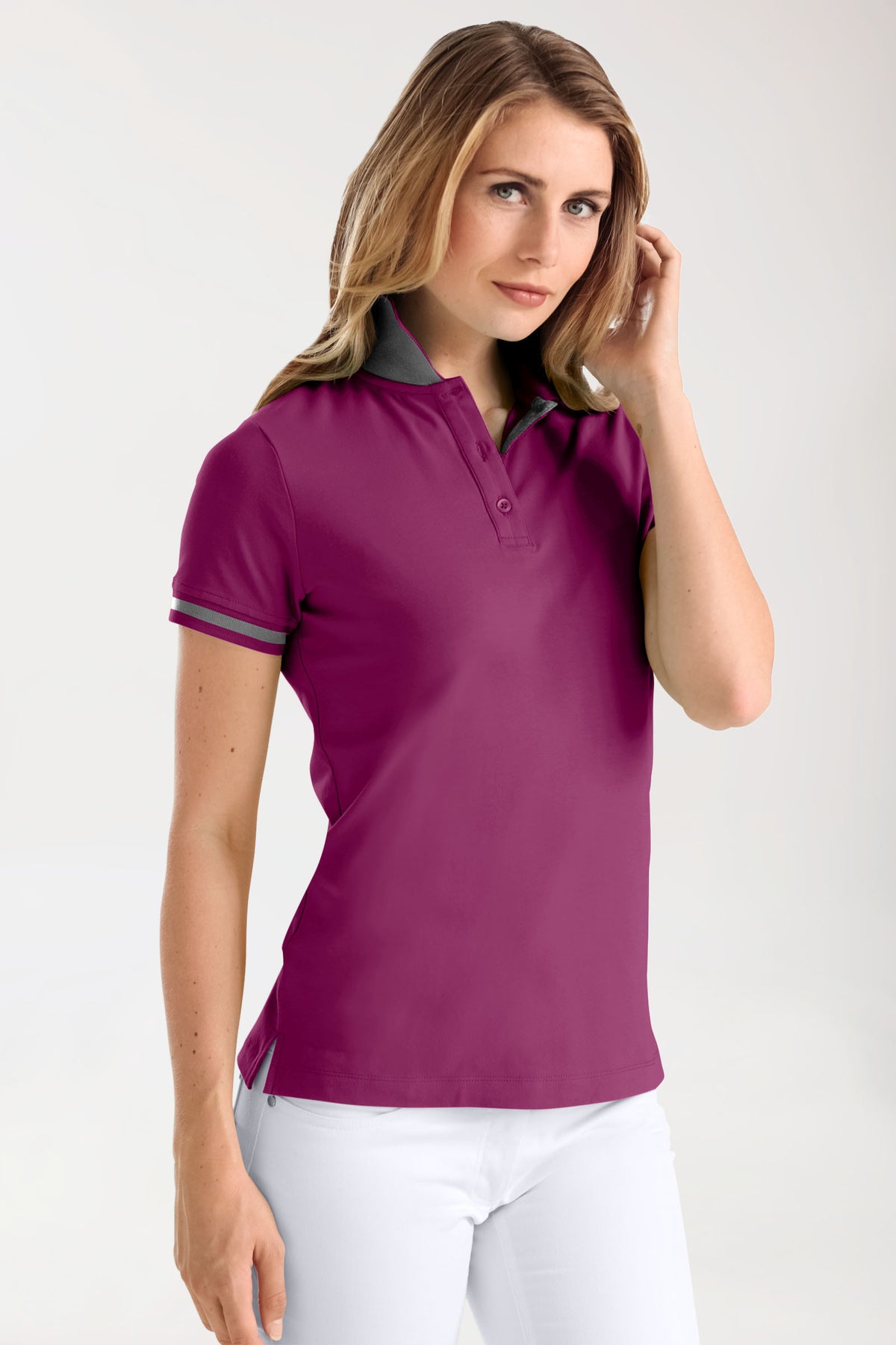 Eine Frau trägt das Stretch Shirt Damen – Polokragen berry/dunkelgrau melange, ein tailliertes, kurzärmeliges Polohemd in der Farbe berry mit dunkelgrauem Kontrastkragen und Ärmelbündchen.
