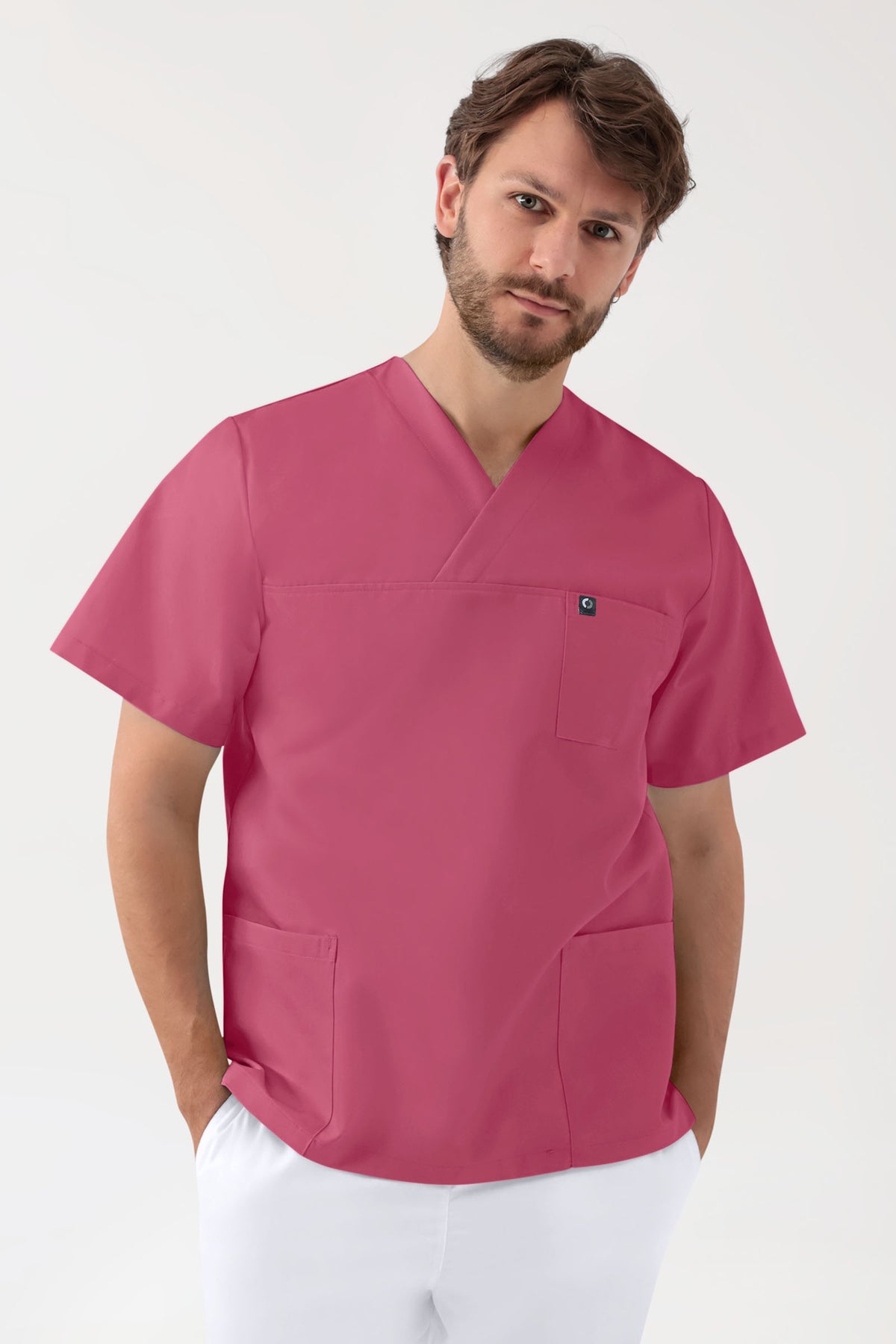 Ein Mann, der einen staubrosa, kurzärmeligen, grünen Stretch-Schlupfkasack (Unisex) mit V-Ausschnitt in der Farbe Rosenholz trägt, der über eine Brusttasche und zwei Seitentaschen verfügt., Vorderansicht