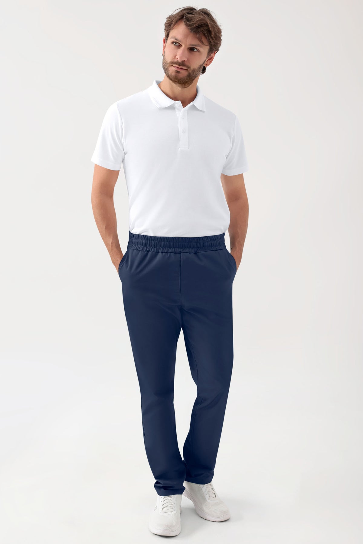 Ein Mann, der ein weißes Poloshirt und eine GRÜNE Stretch-Hose Unisex – Rundumgummibund in Marineblau mit lässiger Beinweite trägt., Vorderansicht