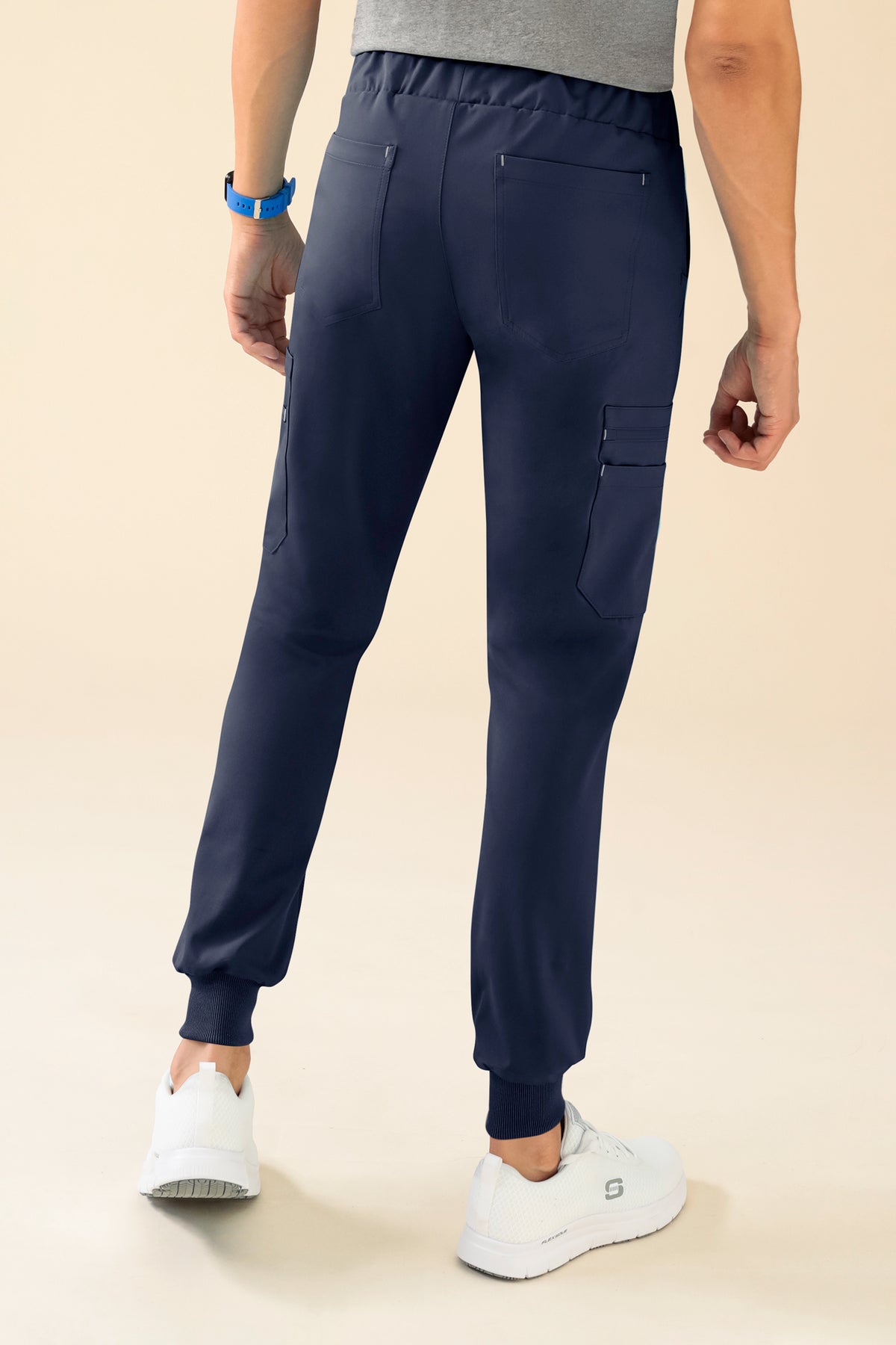 Rückansicht der marineblauen KAERE-Herrenhose – Scrub-Hose mit Saumbündchen und Beintaschen, kontrastfarbenen Nähten, Seitentaschen an den Beinen, gerippten Bündchen an den Knöcheln und einer antimikrobiellen Ausrüstung.