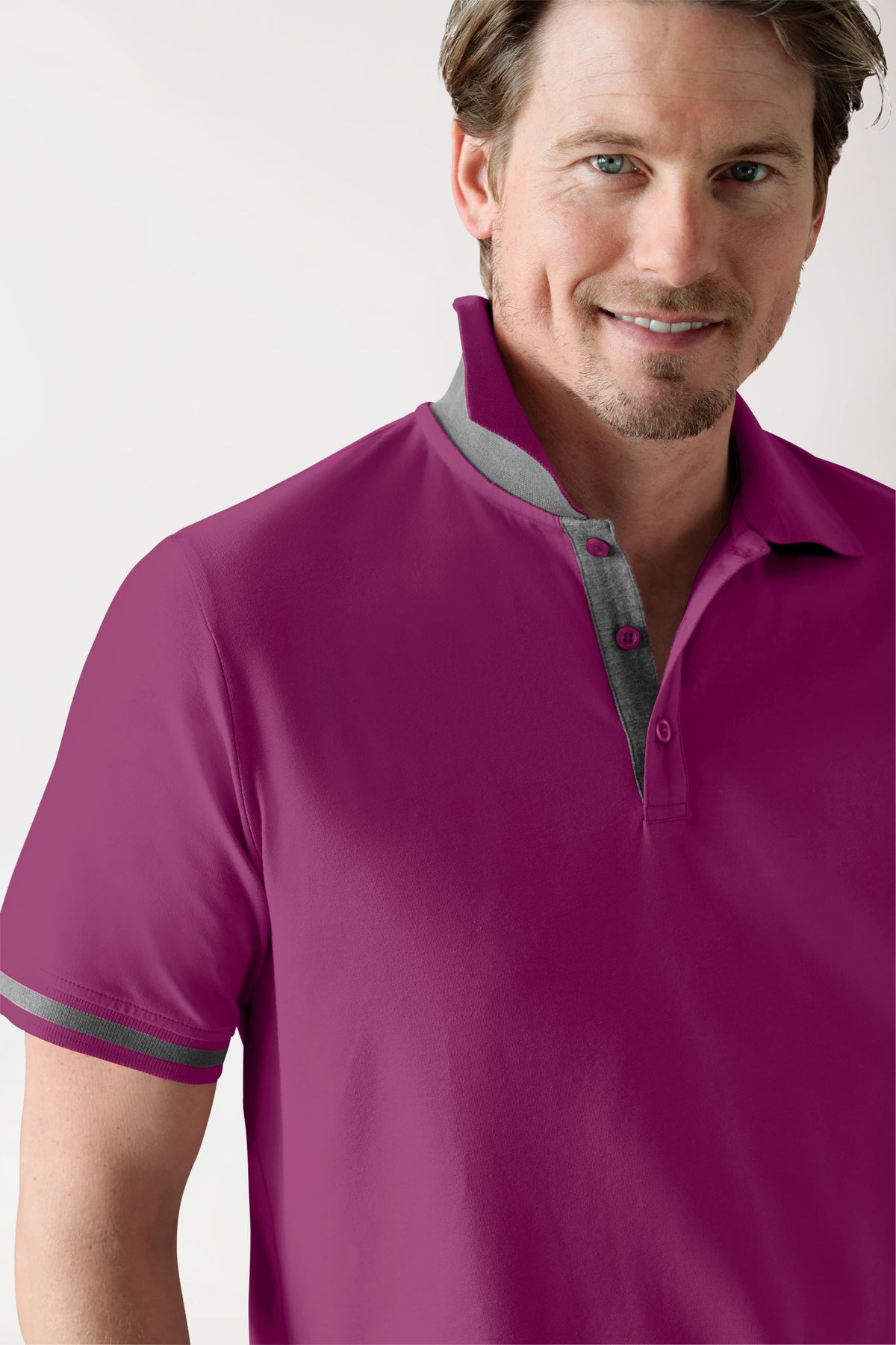 Ein Mann, der ein CLINIC DRESS Stretch Shirt Herren – Polokragen berry/dunkelgrau melange trägt, ein beerenfarbenes, kurzärmeliges Poloshirt mit grauem Kragen, Knopfleiste und Ärmelbündchen.