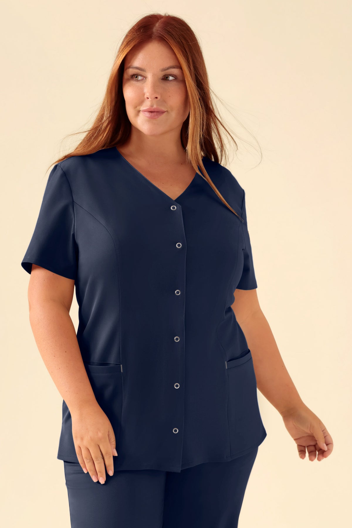 Marineblaues KAERE Kasack-Oberteil für Damen – durchgeknöpftes Scrub-Top mit V-Ausschnitt, kurzen Ärmeln, Knopfleiste vorne und Seitentaschen., Vorderansicht Das Model ist 173 cm groß und trägt Größe XL