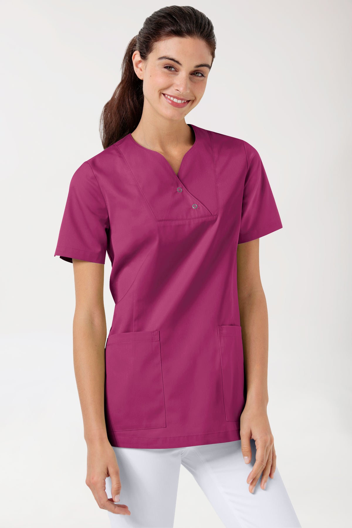 Eine Frau, die ein beerenfarbenes CLINIC DRESS CORE Schlupfkasack Damen Curved Fit – mit Druckknöpfen trägt, mit gekerbtem V-Ausschnitt, kurzen Ärmeln und zwei Druckknöpfen.