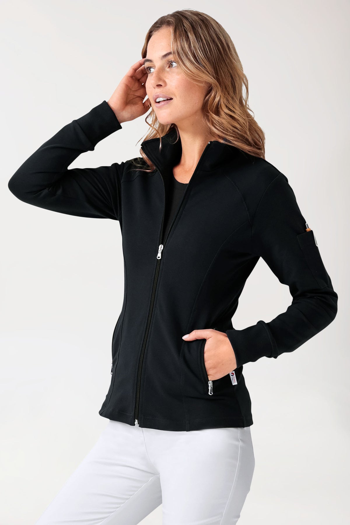 Eine Frau, die eine schwarze CLINIC DRESS Sweatjacke für Damen – Stehkragen, schwarz – mit Reißverschluss, Stehkragen und einer Armtasche trägt.