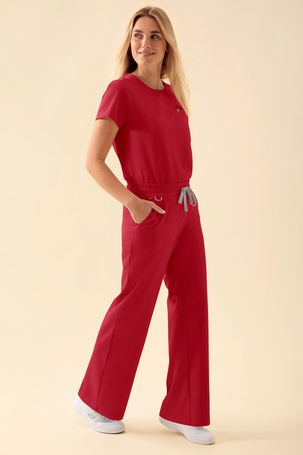 Eine Person, die ein passendes rotes Set aus einem kurzärmeligen Oberteil und einer weit geschnittenen Hose von KAERE (Damen – weites Bein, rot) mit lässigem Kordelzug in der Taille trägt.