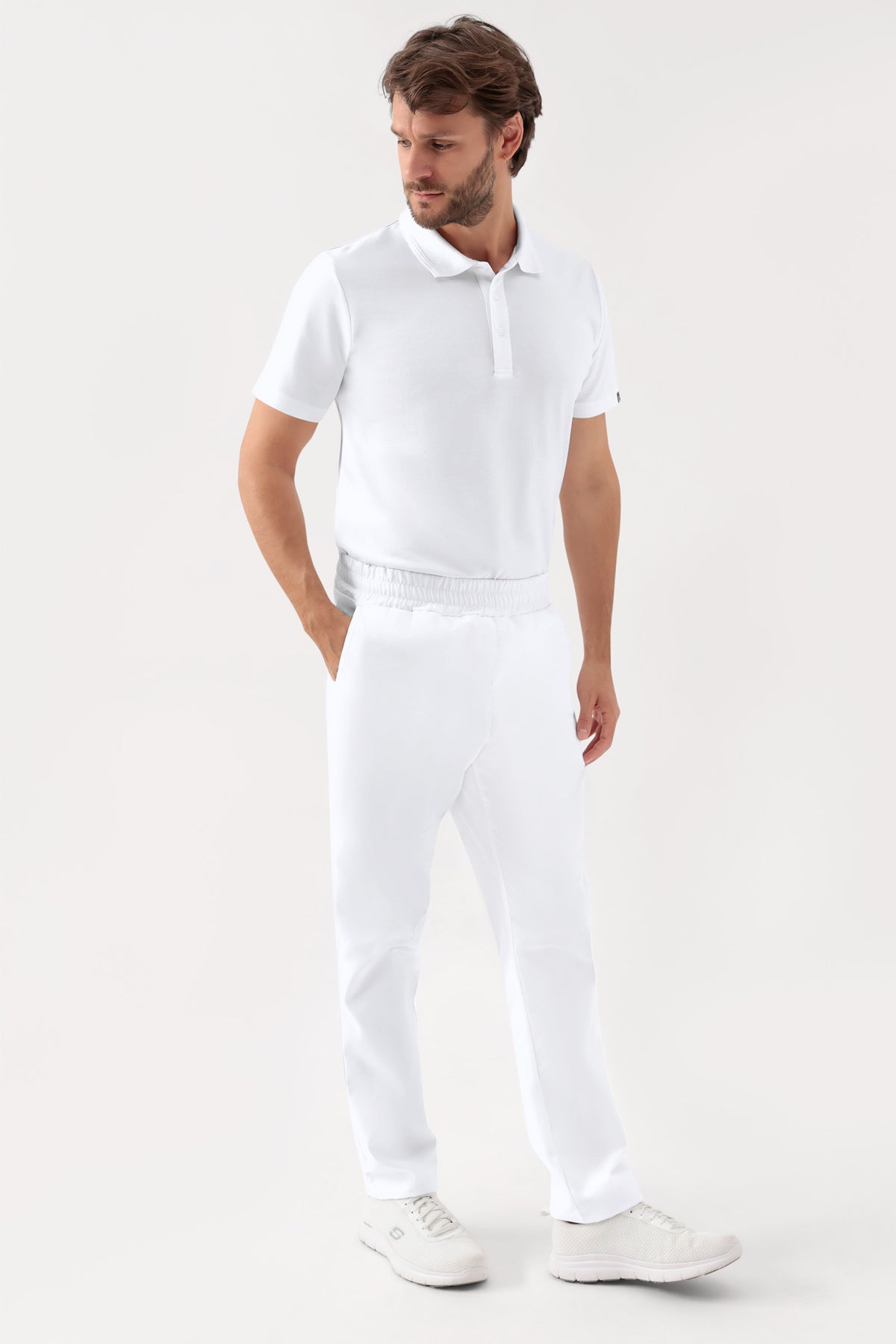 Ein Mann, der ein weißes Poloshirt, weiße Turnschuhe und eine grüne Stretchhose Unisex – Rundumgummibund weiß in lässiger Passform trägt., Vorderansicht 